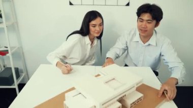 Becerikli mimari mühendisi ekip ölçümü ve ev modeline birlikte çalışırken karar verme ve toplantı odasındaki bina yapısı ve planlarla ilgili tartışmalar. Tertemiz..