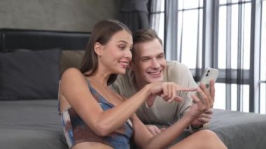 Genç çift, online ödeme uygulaması ve dijital cüzdanı kullanarak kredi kartıyla ödeme yaptıktan sonra mutlu ve heyecanlı hissediyorlar. Mobil internet üzerinden alışveriş ve modern alımlar. Düzenle