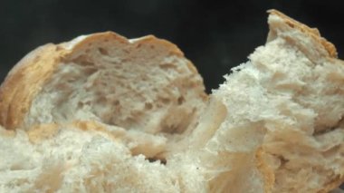 Koyu arkaplanda taze ekmek parçacıkları var. Tahta tepsiye yerleştirilmiş ekmeğin makro fotoğrafçılığı. Kamera hareketini yakınlaştır. Gurme ve fırın konsepti. Poster için tasarım, yemek blogu. Pabulum.