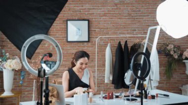 Kadın nüfuzlu kişi video görüntülerini canlı yayınlıyor. Sosyal medya ya da blog. Stüdyo ışıklandırması olan mutlu genç bir kız pazarlama için internet üzerinden yayın yapıyor..