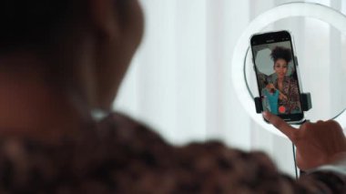 Arkadan bakıldığında kadın nüfuzlu kişi canlı yayın vlog görüntülerini çeker. Önemli sosyal medya ya da blogu gizler. Stüdyo ışıklandırmalı bir kız çevrimiçi pazarlama oturumu yayını için.