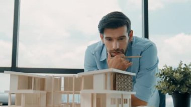 Akıllı Kafkasyalı mühendis veya proje yöneticisi ölçüm, teftiş, panorama penceresinin yanında, gökdelen manzaralı ev modeline bakın. Yönetici tasarım evi inşaatı. İzleme