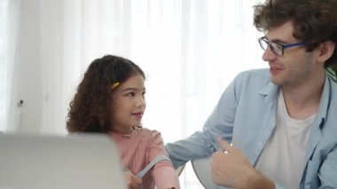 Kafkasyalı baba kızına bakıyor ve gülümseyen Amerikalı kız kulağına kalem geçirip dikkatle dinlerken dizüstü bilgisayarla yapay zeka üretmekten bahsediyor. Mutlu aile öğrenimi birlikte. Pedagoji.