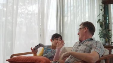 Büyükbaba ve torun birlikte konsol oyunu, eğlence medyası oynuyorlar. Eski kullanım teknolojisi yeni nesil ile iletişim kurar. Nesiller arası uçurum aile bağını güçlendirir. Uyumsuzluk.