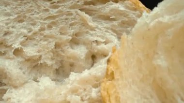 Koyu arkaplanda yırtık taze ekmek parçalarını yakın plan çek. Tahta tepsiye konmuş Fres ekmeklerinin makro fotoğrafları. Yakınlaştır ve kamera hareketini döndür. Gurme ve fırın konsepti. Pabulum.