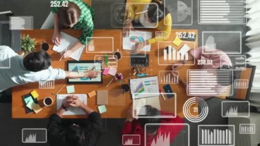 Üst görünüm yöneticisi dizüstü bilgisayarı elinde tutuyor ve yatırımcı dinlerken borsa istatistiksel hologramıyla finansal grafiğini sunuyor. Toplantı odasında oturan müdürün hava görüntüsü. Cemaat.