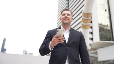 Kafkasyalı iş adamı şehir merkezinde dururken cep telefonlarını kontrol ediyor ve pazarlama ekibinden satış raporlarını inceliyor. Yetenekli bir yönetici cep telefonu üzerinde çalışıyor ve veri analizine bakıyor. Urbane.