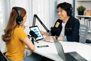 Gülümseyen radyo etkili sunucusu kulaklık takıyor kadın konuşmacı sosyal medya online canlı yayın kanalı ile röportaj yapıyor tablet ekranla konuşarak sabah stüdyo kaydındaki bağlantıyı paylaşıyor. İnfobahn.