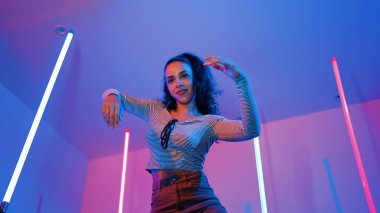 Latin dansçıların kameraya bakıp şehrin pop müziğiyle dans ettiği düşük açılı kamera. Profesyonel çekici hipster, mor veya neon ışıklı hip hop şarkısına geçiyor. Şık bir kumaş. Mutluluk.