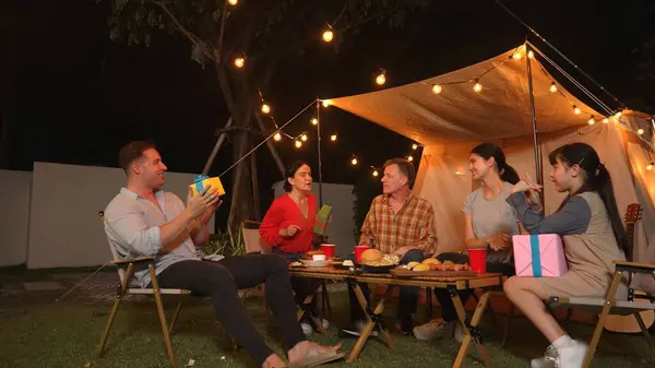 Stock image Family together celebrate anniversary in garden. Senior give gift to granddaughter. Outdoor camping activity to relax with relatives, spend time with multigeneration cross generation gap. Divergence.