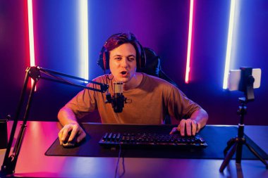 Oyun kanalı, online oyun oynayan akıllı flamalı oyun sunucusu, kulaklık takan, neon ışıklandırma odasındaki takım oyuncusuyla akıllı telefondan canlı yayında konuşan izleyiciler. Bireysel.