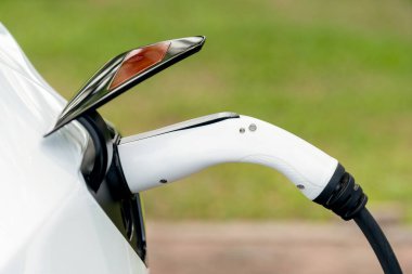 Temiz ve sürdürülebilir enerji kullanarak şarj olmak için EV şarj cihazına EV şarj cihazı takıldı. Doğal koruma ve çevre dostu araba yolculuğu konsepti. Yükselt