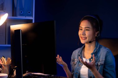 Sunucu kanalı Asyalı etkileyicisi canlı yayında konuşuyor. Sosyal medyada kulaklık takıyor, bilgisayar kaydı yapıyor, dinleyicileri selamlıyor ve Neon Modern Stüdyoları 'nda online olarak koçluk yapıyor. Taktik.