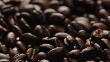 Siyah arkaplanlı taze kahve çekirdeğinin makro çekimi. Etrafı sarılmış aromatik kavrulmuş kahve tohumu yığınlarına yakın. Makrografi. Fasulyeler etrafa saçılıyor. Geliştirilebilir.