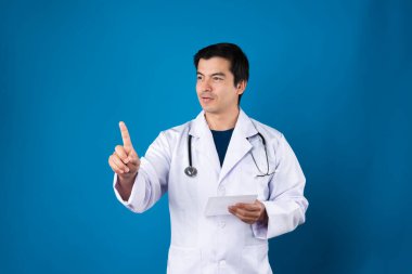 Akıllı doktor, elinde şeffaf tablet, hastalık araştırması verileri tutarak fütüristik teknolojiyle sağlık hizmetleri yenilik arayüzü hologram monitörü ekranını işaret ediyor. Entrika.