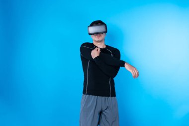 VR kullanan zeki bir oyuncu sağlıklı vücut egzersizi için kollarını uzatarak meta-şehirdeki gelecekteki teknolojik sanal gerçekliğe bağlanan mavi arka plan üzerinde çalışıyor. Entrika.