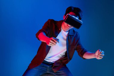 VR kullanan zeki bir oyuncu araba yarışlarında araba sürerken yeni dünyaya dönüyor mavi neon ışıklı duvar bağlantılı fütüristik teknoloji sanal gerçeklik meta 'sını izole ediyor. Entrika.