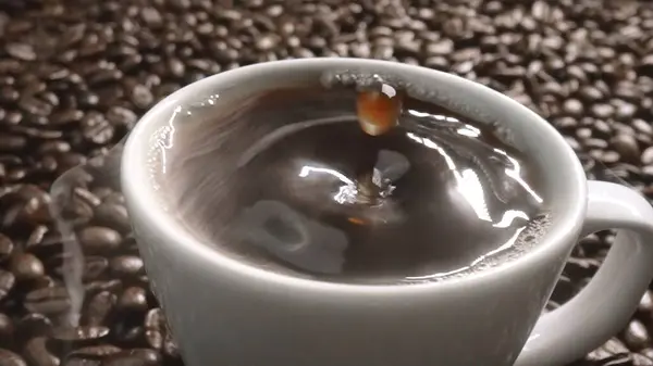 stock image Close up of coffee bean drop in to hot espresso with pile of coffee seed. Macro of freshly roasted bean falling in to cup with aromatic smoke. Slow motion. Organic coffee seed concept. Comestible.