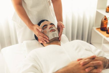 Kaplıca salonunun sakin, modern gündüz atmosferi. Kadın müşteri yüz maskesi takarak kendini yenilemeye çalışıyor. Yüz bakımı ve güzellik kozmetolojisi prosedürü. Sessiz.