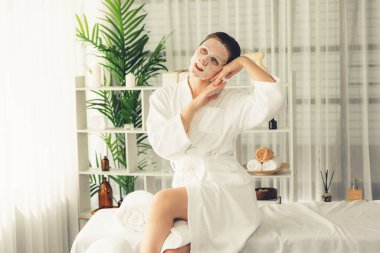 Kaplıca salonunun sakin, modern gün ışığı atmosferi, kadın müşteri poz veriyor ve yüz maskesi ile gençleştiriyor. Yüz bakımı ve güzellik kozmetolojisi prosedürü. Sessiz.