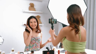 Etkilenen iki ortak canlı yayın yapan video görüntülerini sosyal medya ya da blog üzerinden gözden geçirir. Canlı kozmetik stüdyosu ışıklandırması olan mutlu genç bir kız pazarlama için internet üzerinden yayın yapıyor..