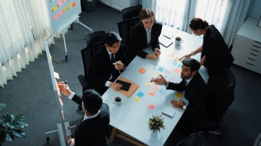 Akıllı yönetici finansal grafiğinin üst görüntüsünden çeşitli takımlara geçerken, bir grup çok kültürlü iş adamı toplantıda hisse yatırım grafiği kullanarak pazarlama stratejisi planlıyorlar. Müdürlük.