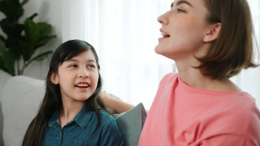 Mutlu anne oturma odasında otururken kızıyla deneyim paylaşıyor. Kafkas anne ve mutlu çocuk konuşuyorlar ve birlikte vakit geçiriyorlar. Çekici kız gülümserken ebeveyn hikayesini dinler. Pedagoji.