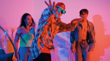 İspanyol hipster renkli kıyafetler giyer ve serbest stil müziğe el sallar. Profesyonel break dansçı neon ışıklarıyla ve modern stüdyo arkadaşlarıyla coşkuyla dans ediyor. Mutluluk.