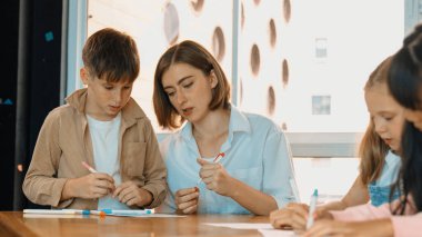 Çizim kitabında işaret kullanarak çeşitli öğrencilerin ve zeki öğretmen çizimlerinin panorama çekimi. Sanat dersinde çizim kitabını kullanarak çok kültürlü bir öğrenci. Rahatlama. Etkinlik.