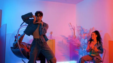 Çok kültürlü bir arkadaş kürsüde otururken Asyalı yetenekli bir dansçı modern müziğe geçiyor. Profesyonel dansçı, hipster takımı tezahürat yaparken ve desteklerken enerjik adımlar atıyor. Mutluluk.