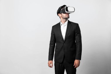 VR gözlüklü yetenekli bir proje yöneticisi ayakta dikilip etrafa bakıyor. Beyaz iş adamı takım elbise giyerken metaevren ve sanal gerçeklik dünyasına bağlanıyor. Yenilik teknolojisi. Sapma.