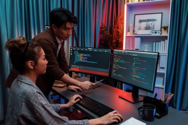 Bilgi teknolojisi geliştiricileri modern ofisteki neon ışık odasında verileri çevrimiçi olarak çalıştıran akıllı web sitesi geliştirme kodlayıcı sistemine işaret ediyorlar. İnfobahn.