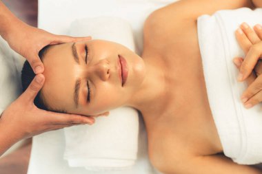 Kafkasyalı kadın stres önleyici kafa masajından ve lüks tatil beldesi ya da otel spa salonundaki modern ışık ortamında yüz güzelliği eğlencelerini şımartmaktan hoşlanıyor. Sessiz.