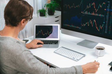 Bilgisayar ve dizüstü bilgisayarı kullanarak, çalışma masasındaki dinamik artırılmış borsa grafiğinin en yüksek kar değerini araştıran bir tüccar, modern ofisteki ekrandaki döviz kuru değerini analiz ediyor. Bireysel.