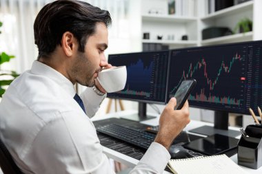 Elinde telefon dinamiğine odaklanan kahve fincanı tutan borsa yatırım ekranı veri analizini karşılaştırarak iç işlerinde yüksek kârlı finans teknolojisi pazarına yatırım yapıyor. Tahmin et..