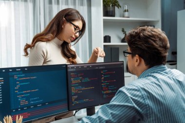 Masada çalışan erkek programcının karşısında duran kadın meslektaşım iki bilgisayar ekranında kodlama web sitesi yazılım sistemi projesini tartışmak için tam yığın veri dizaynı ile karşılaştırıyor. Varsayım.