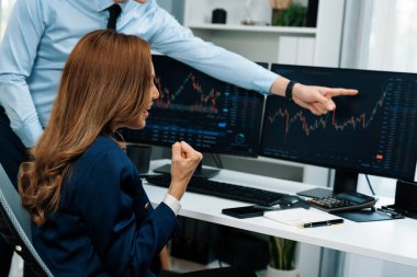 Başarılı gülümseyen Asyalı iş ortakları borsa veritabanında kârlı bir proje için el ele tutuşuyorlar. Yan görüntüdeki modern ev ofisinde resmi takım elbise giyiyorlar. İnfobahn.