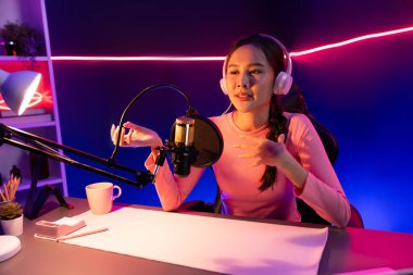 Geceleri podcast 'te olumlu konuşmalar yapan, pembe neon ışıklı modern stüdyoda sunum için dizüstü bilgisayar kullanan, gülümseyen, genç, güzel Asyalı bir etkileyiciydi. Taktik.