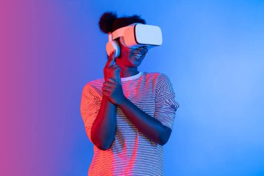 VR kullanan Afrikalı bir oyuncuyu avlamak, meta-evrende silah ateşleme oyunu oynamak, mavi neon ışığını izole etmek, zafer hayvanı avlamak, fütüristik teknoloji hologramı sanal gerçekliği. Entrika.
