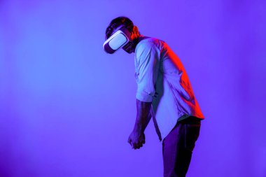 VR gözlüklü beyaz adam golfte hareket ediyor ve neon arka planda duruyor. Profesyonel oyuncu sanal dünyaya fütüristik teknoloji yeniliğiyle giriyor. Sapma.