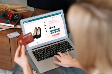 Genç bir kadın internet bankacılığı için kredi kartıyla dizüstü bilgisayar kullanıyor. Evinde online ödeme kapısı ile E ticareti yapıyor. Banka kartıyla modern ve kullanışlı online alışveriş. Blithe