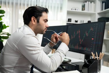 Akıllı tüccar işadamı, modern merkez ofisindeki araştırma pazarında en yüksek kârlı finansal teknolojiye yatırım yaparak bilgisayar üzerinde iki dinamik borsa yatırım ekranını analiz ediyor. Tahmin et..