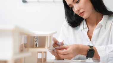 Modern ofise odaklanarak ev modelini üçgen ölçekte ölçen profesyonel, güzel mühendis mimarın yakın plan portresi. İş yaratıcı tasarım konsepti. Tertemiz..