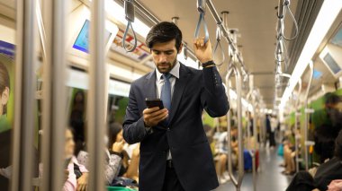 Trende insanlarla çevrili dururken telefona bakan profesyonel bir iş adamı. Kafkas proje yöneticisi e-postaları kontrol ediyor, arka planı bulanık pazarlama stratejisi planlıyor. Sevinçli..