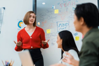 Kafkasyalı genç bir iş kadını, pazarlama stratejisini zihin haritası kullanarak sunuyor, soruları kendinden emin bir şekilde cevaplarken grafiğini çiziyor. Takım çalışması, beyin fırtınası, tartışma konsepti. Tertemiz..