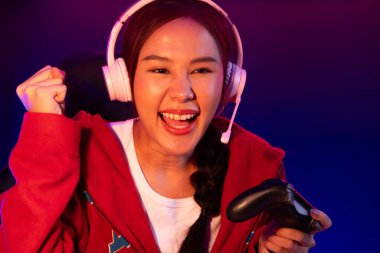 Neon odada kulaklık takan yetenekli Esport takım oyuncularını yumruklayarak oynayan güzel Asyalı kız flamasının sunucu kanalı. Taktik.