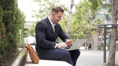 Kafkasyalı iş adamları laptopta çalışırken saati kullanarak toplantıyı hatırlatıyorlar. Proje yöneticisi, uzaktan kumandalı iş ekibiyle çalışırken bilgisayar yazma raporunu kullanıyor. Urbane.