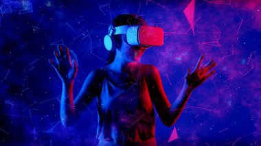 Heyecanlı gülümseyen Asyalı kadın VR metaevrenine bakıp mavi neon dijital evreni işaret ederek yıldızlı zodyak sanal uzay fantastik keşif nebulası meta-dünya. Halüsinasyon.
