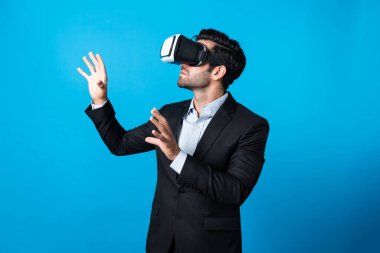 İş adamı VR gözlüğü kullanarak veri analizi yapıyor. Proje yöneticisi iş stratejisini mavi arka planda takım elbise giyerken metaverse ya da sanal gerçeklik dünyasına girerek kontrol ediyor. Sapma.