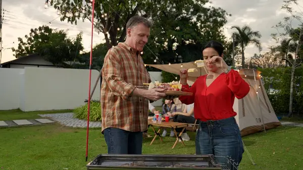 stock image Family all together camp in garden, Old couple grill food for family member. Outdoor camping activity to relax with tasty meal and spend time with young generation cross generation gap. Divergence.